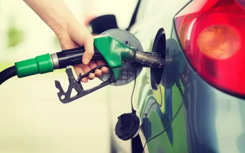 Mano che inserisce la pompa di benzina nel serbatoio. Spero di non aver messo 3 litri di benzina nel diesel!