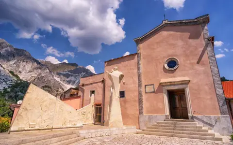 Monumento ai cavatori e chiesa a Colonnata, con le Alpi Apuane sullo sfondo. Un luogo suggestivo da scoprire, tra arte e storia.