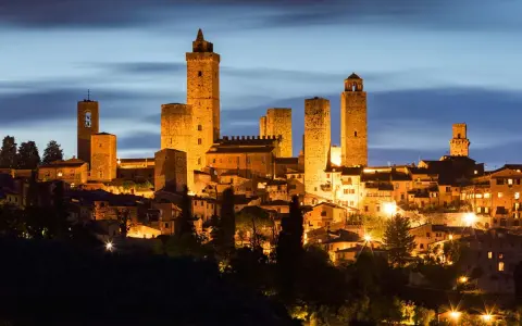 San Gimignano, una delle città più belle della Toscana, illuminata di notte con le sue iconiche torri medievali che svettano nel cielo.
