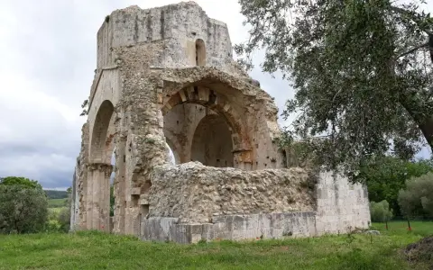 Rovine suggestive a Magliano in Toscana, cosa vedere: un'antica abbazia in pietra con archi crollati e vegetazione rigogliosa.