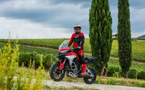 Motociclista in tenuta da gara su una Ducati, pronto per itinerari moto Toscana 1 giorno tra vigneti e cipressi.