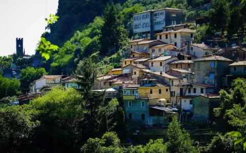 Case colorate e tetti rossi si aggrappano alla collina a Casoli di Camaiore, circondate da un verde lussureggiante.