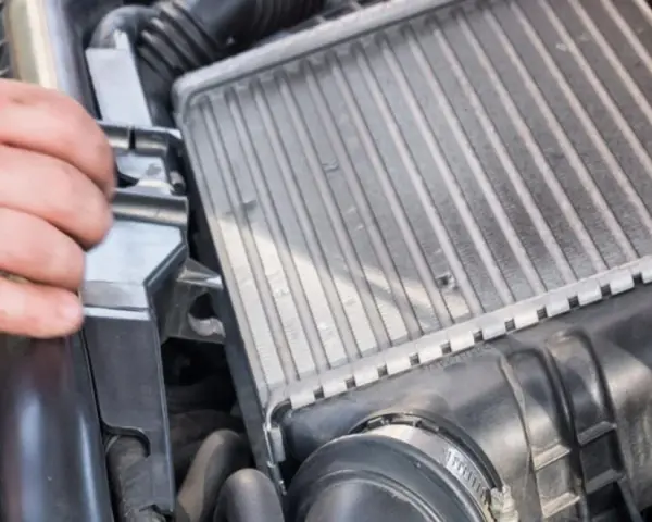 Mano che controlla un intercooler che sfiata, parte essenziale del sistema di sovralimentazione di un motore.