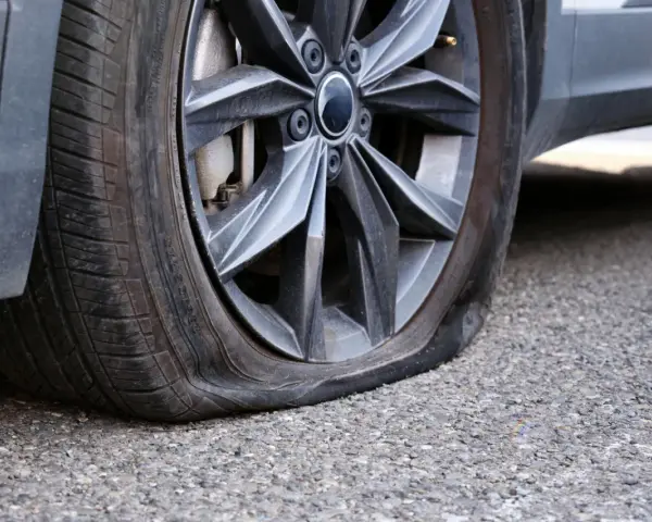 Ruota dell'auto con pneumatico sgonfio, mostra un'ernia evidente. Un problema comune che richiede attenzione immediata.