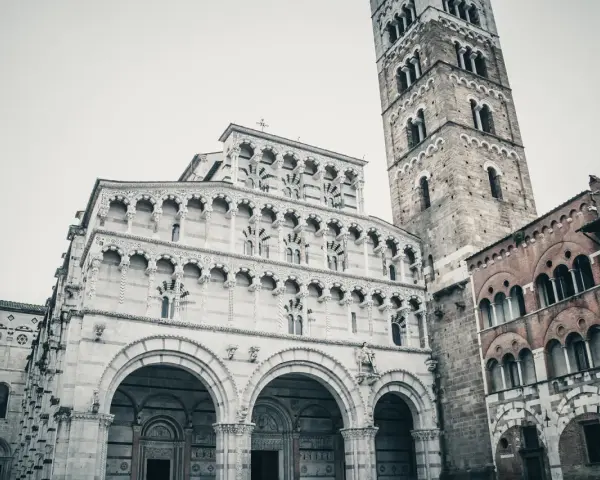 La cattedrale di San Martino a Lucca, con la sua imponente facciata in marmo bianco e il campanile romanico, domina la piazza.