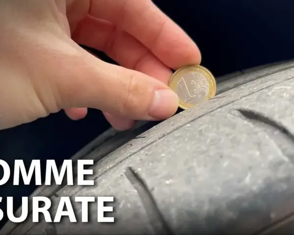 Una mano inserisce una moneta da 1 euro in un pneumatico usurato, indicando che è consigliabile sostituire gli pneumatici per la sicurezza.