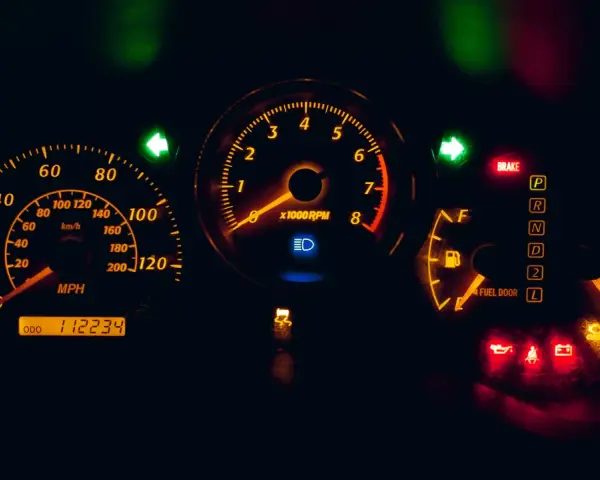 Cruscotto auto illuminato di arancione: tachimetro, contagiri, indicatori di marcia e spie accese, tra cui una spia arancione macchina.