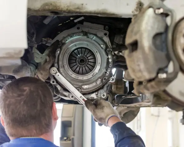 Meccanico lavora sulla frizione di un'auto. La durata della frizione varia, ma si consiglia di controllarla ogni quanti km si cambia la frizione.