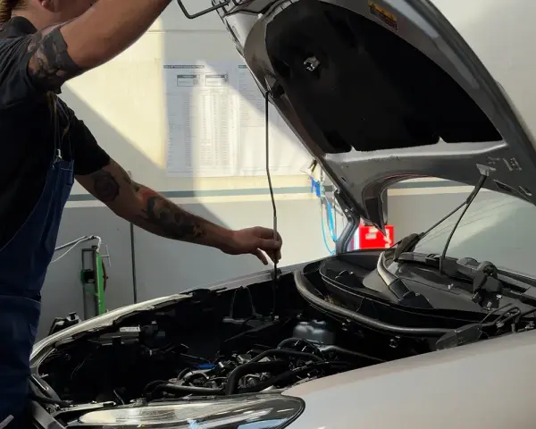 Meccanico con tatuaggi controlla il motore. Per sapere tagliando auto ogni quanto, consulta il libretto o chiedi al tuo meccanico di fiducia.