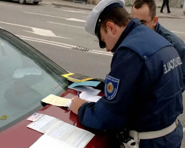 Agente di polizia scrive verbale su un'auto con revisione scaduta da 2 anni. Documenti e patente sul cofano.
