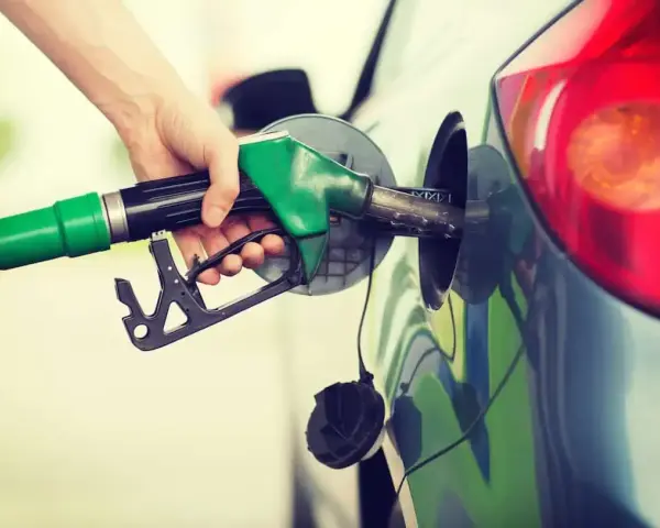 Mano che inserisce la pompa di benzina nel serbatoio. Spero di non aver messo 3 litri di benzina nel diesel!