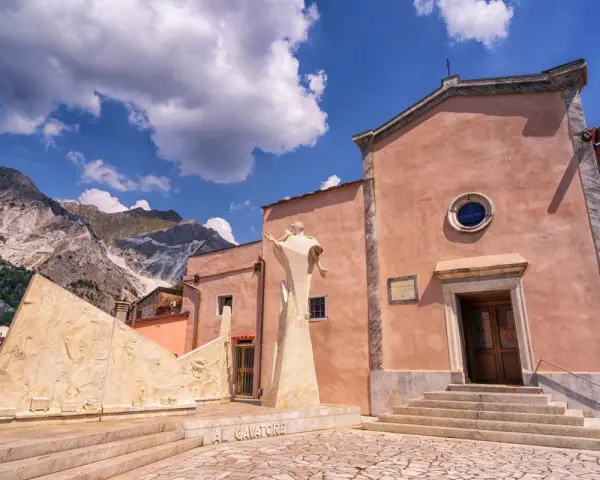 Monumento ai cavatori e chiesa a Colonnata, con le Alpi Apuane sullo sfondo. Un luogo suggestivo da scoprire, tra arte e storia.