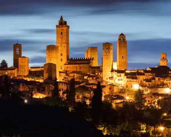San Gimignano, una delle città più belle della Toscana, illuminata di notte con le sue iconiche torri medievali che svettano nel cielo.