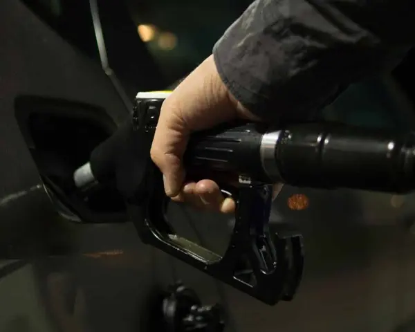 Mano che inserisce la pistola del carburante nel serbatoio dell'auto. Potrebbe indicare una pompa della benzina rotta o sintomi di malfunzionamento.