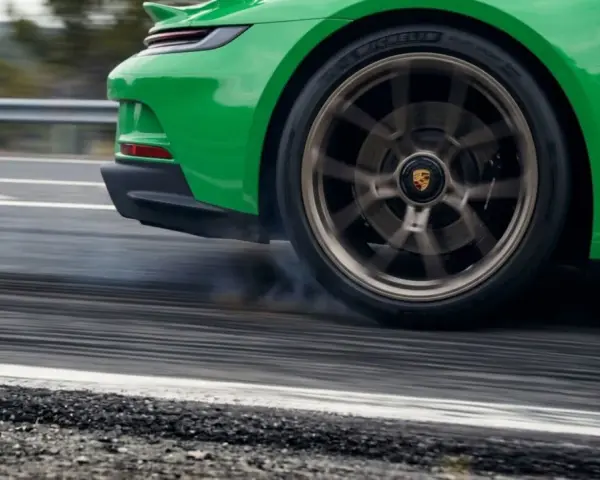 La ruota di un'auto sportiva verde lascia strisce sull'asfalto, producendo un rumore rotolamento pneumatici a bassa velocità.