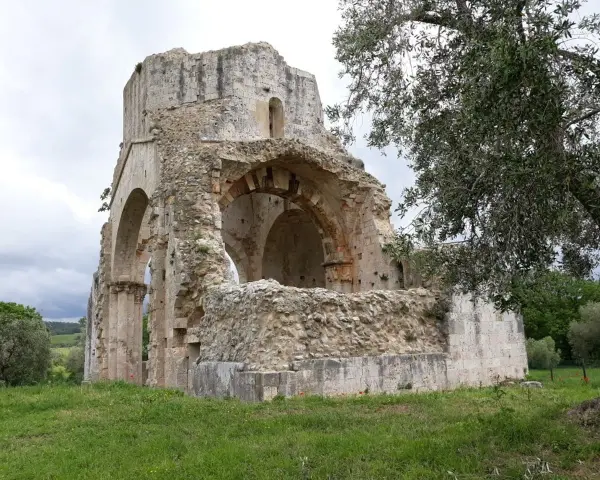 Rovine suggestive a Magliano in Toscana, cosa vedere: un'antica abbazia in pietra con archi crollati e vegetazione rigogliosa.