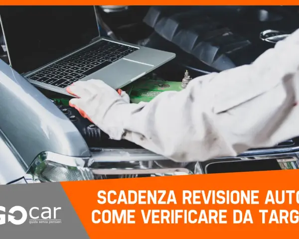 Meccanico con guanti controlla la scadenza della revisione auto tramite laptop, con il cofano aperto.
