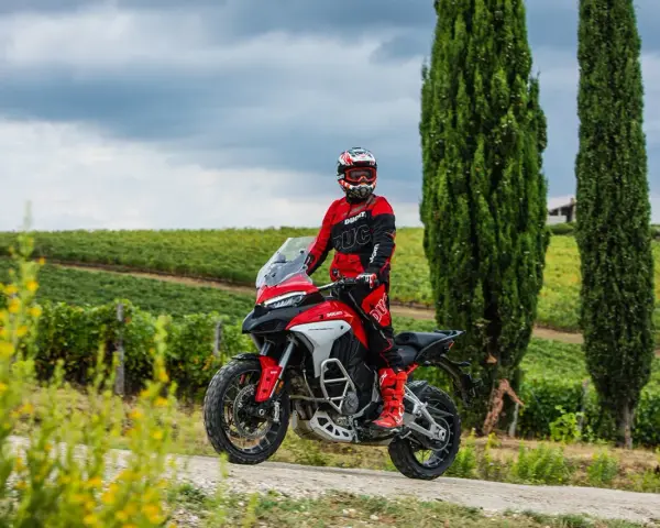 Motociclista in tenuta da gara su una Ducati, pronto per itinerari moto Toscana 1 giorno tra vigneti e cipressi.