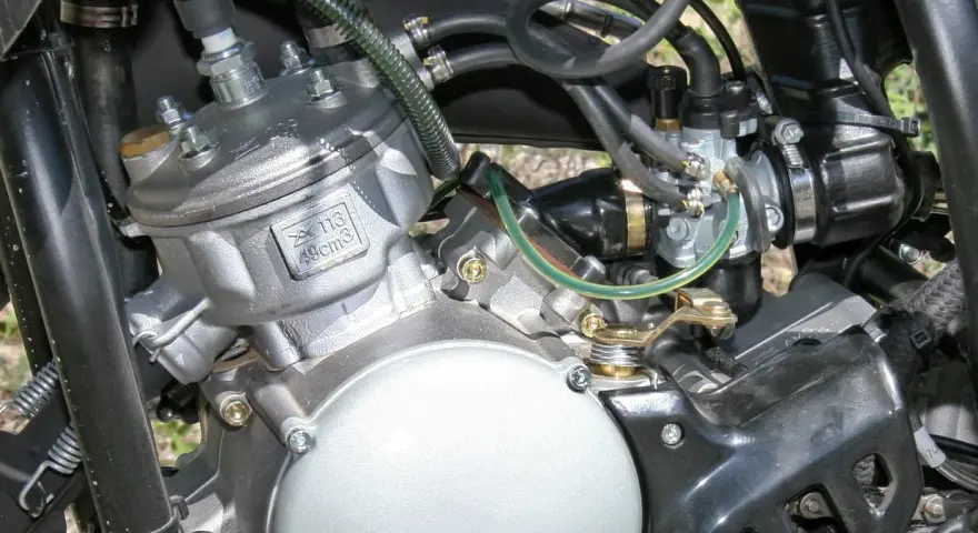 Dettaglio motore 49cc, con carburatore e candela. Potrebbe essere utile per diagnosticare sintomi motore aspira aria.
