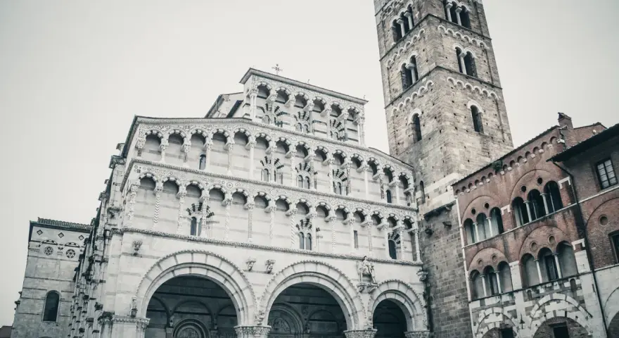 La cattedrale di San Martino a Lucca, con la sua imponente facciata in marmo bianco e il campanile romanico, domina la piazza.