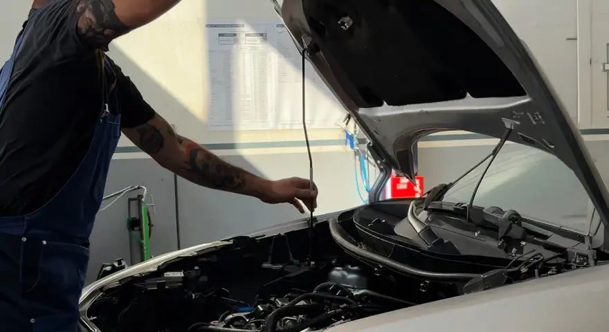 Meccanico con tatuaggi controlla il motore. Per sapere tagliando auto ogni quanto, consulta il libretto o chiedi al tuo meccanico di fiducia.