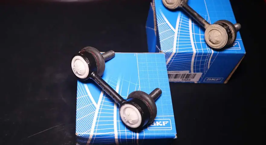 Biellette barra stabilizzatrice rotte sintomi: due nuove biellette SKF su scatole blu, una usata e sporca.
