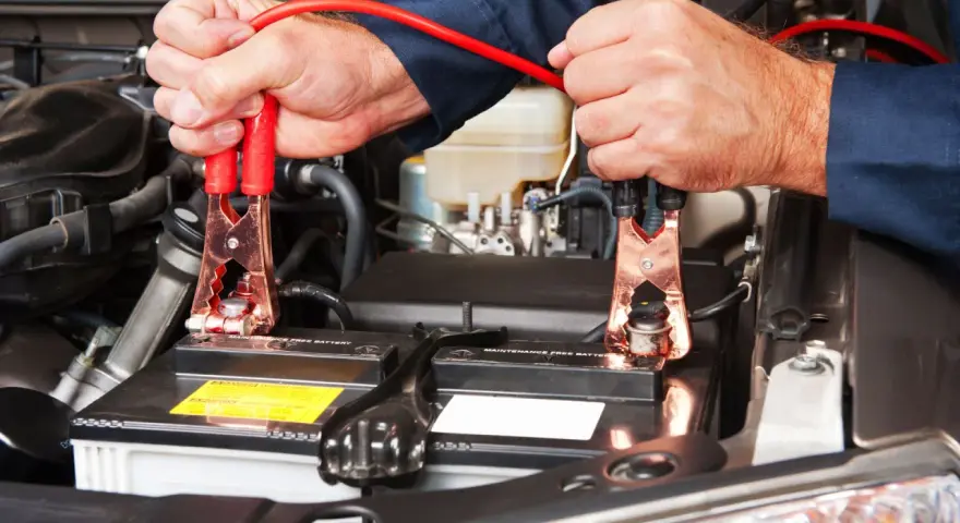 Mani che collegano i cavi alla batteria per capire come far ripartire la macchina.