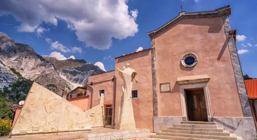 Monumento ai cavatori e chiesa a Colonnata, con le Alpi Apuane sullo sfondo. Un luogo suggestivo da scoprire, tra arte e storia.