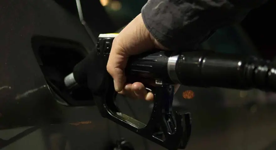 Mano che inserisce la pistola del carburante nel serbatoio dell'auto. Potrebbe indicare una pompa della benzina rotta o sintomi di malfunzionamento.