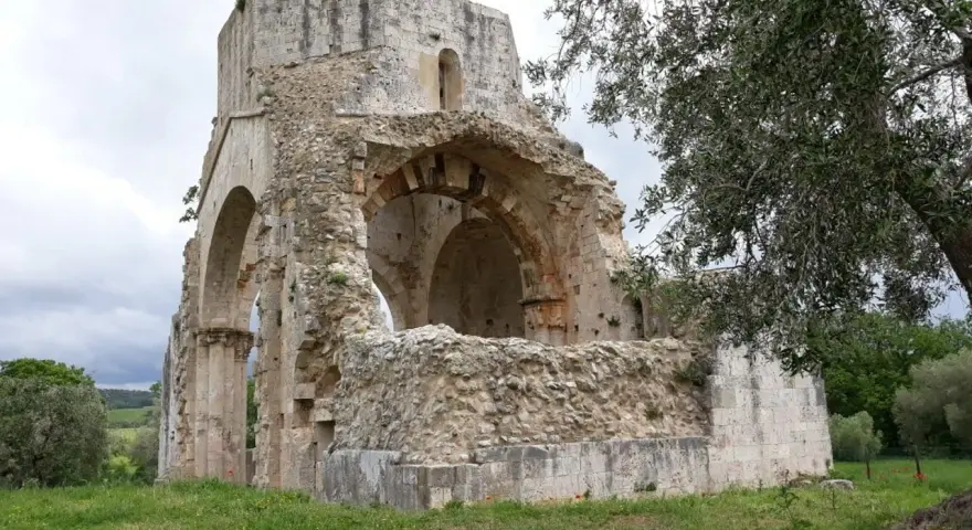 Rovine suggestive a Magliano in Toscana, cosa vedere: un'antica abbazia in pietra con archi crollati e vegetazione rigogliosa.