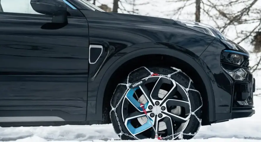 Auto nera su neve con catene sulle ruote motrici per affrontare il ghiaccio.
