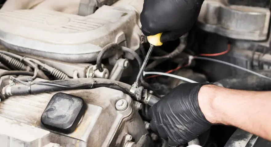 Meccanico con guanti neri lavora sul motore, risolvendo problemi pompa gasolio serbatoio.