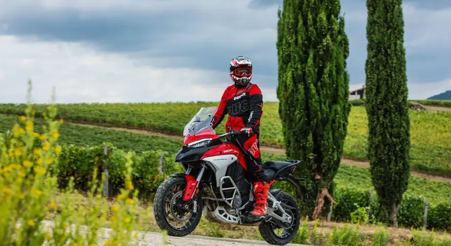 Motociclista in tenuta da gara su una Ducati, pronto per itinerari moto Toscana 1 giorno tra vigneti e cipressi.