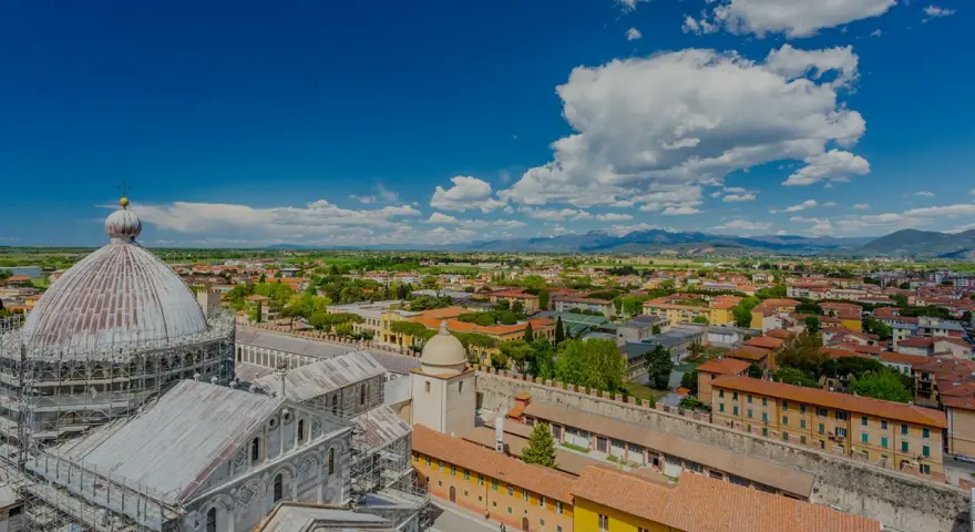 Vista dall'alto della città di Pisa, con la cupola del Duomo in primo piano. Si intravede l'interno della torre di Pisa, con la sua architettura storica.