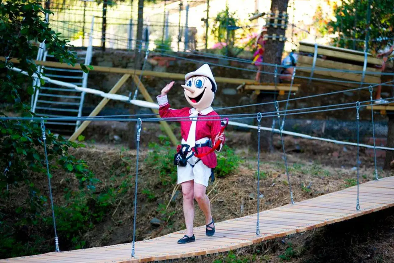 Pinocchio saluta da un ponte tibetano, un'avventura perfetta per un weekend con bambini in Toscana.