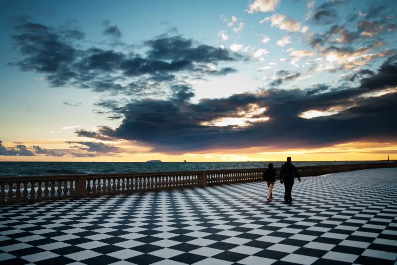 Passeggiata al tramonto sulla Terrazza Mascagni dall'alto, con il mare mosso e un cielo drammatico.