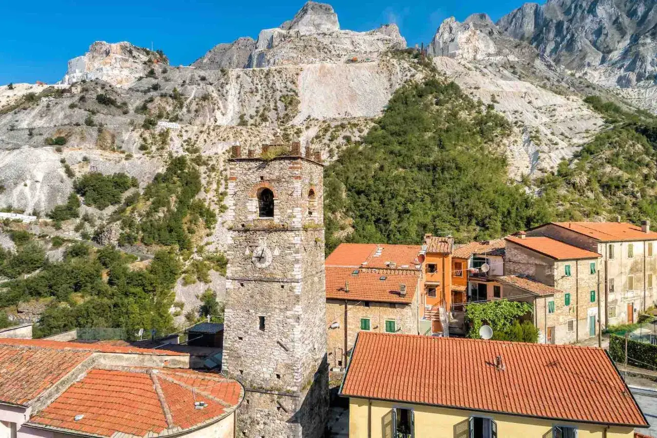 Torre medievale e case con tetti rossi, sullo sfondo le cave di marmo. Ecco cosa vedere a Colonnata, un borgo incantevole.