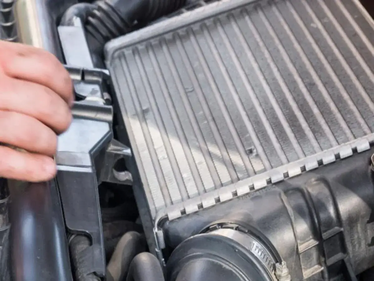 Mano che controlla un intercooler che sfiata, parte essenziale del sistema di sovralimentazione di un motore.