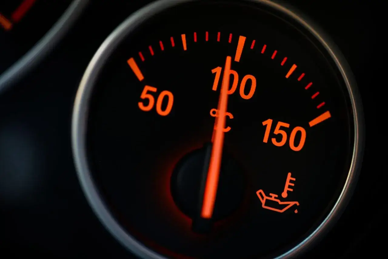 Indicatore temperatura motore su cruscotto auto: la lancetta indica un valore vicino a 100°C, segnalando un potenziale surriscaldamento motore.
