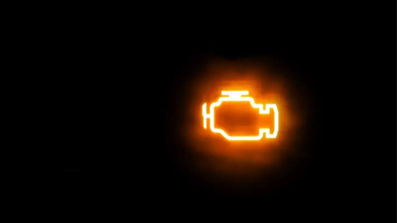 Icona luminosa arancione di un motore su sfondo nero. La spia gialla motore è accesa, segnalando un potenziale problema.