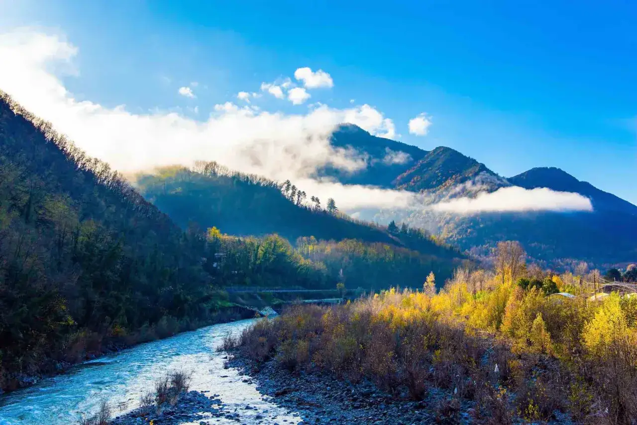 Fiume serpeggiante tra montagne nebbiose e boschi autunnali, un luogo ideale dove andare in montagna in Toscana per ammirare la natura.