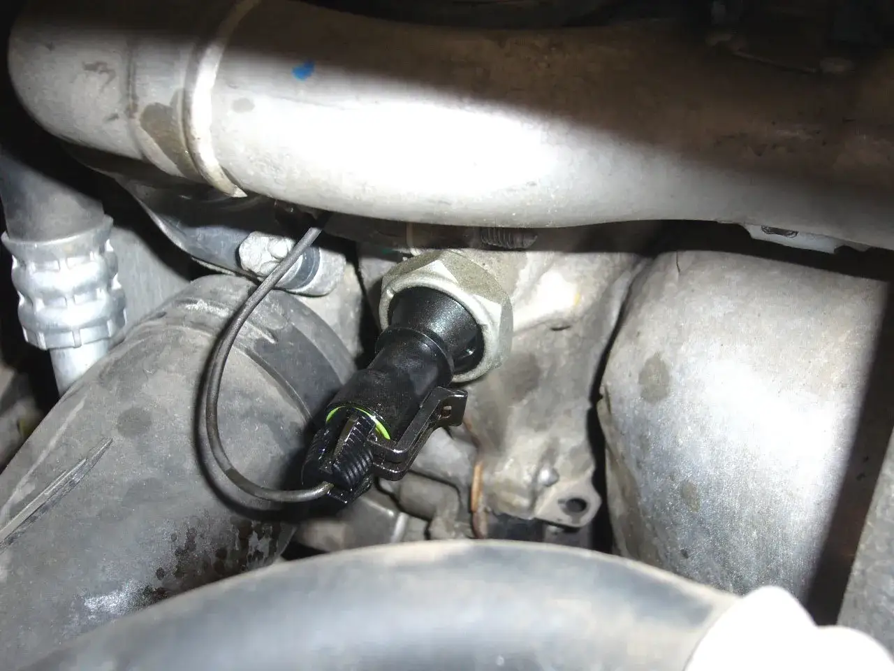 Sensore di pressione olio motore, pronto per la sostituzione bulbo pressione olio. Tubi e componenti metallici in primo piano.