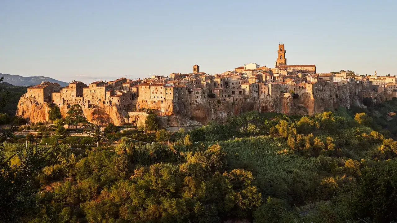 La citt&agrave; del tufo toscana, Pitigliano, si erge maestosa su uno sperone roccioso, illuminata dalla luce dorata del tramonto.