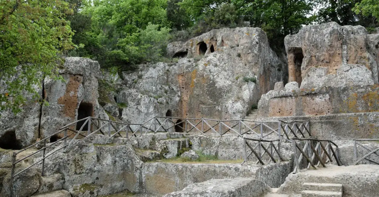 Antiche tombe etrusche scavate nella roccia, parte dei siti etruschi in Toscana, con sentieri e recinzioni in legno.