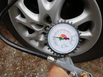 Misura la pressione delle gomme dell'auto: il manometro indica circa 2.5 bar, il valore ideale per gonfiare le gomme.
