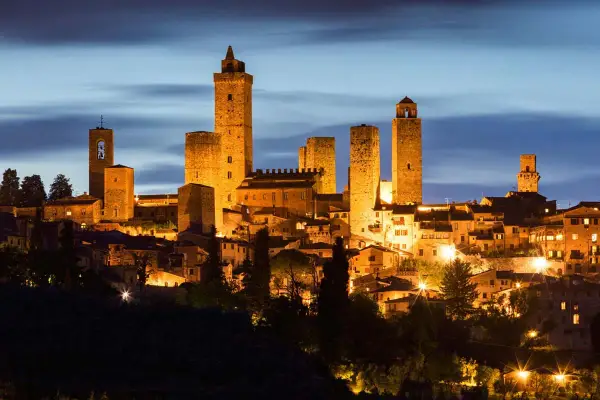 San Gimignano, una delle città più belle della Toscana, illuminata di notte con le sue iconiche torri medievali che svettano nel cielo.