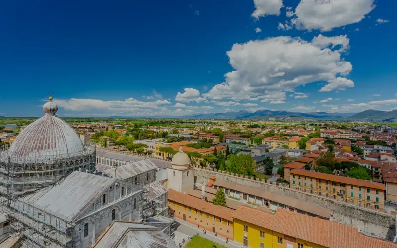 Vista dall'alto della città di Pisa, con la cupola del Duomo in primo piano. Si intravede l'interno della torre di Pisa, con la sua architettura storica.